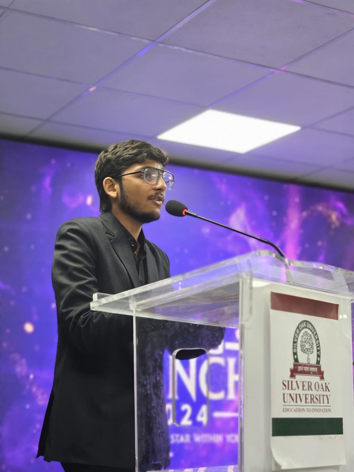 Host speaking at podium with university backdrop